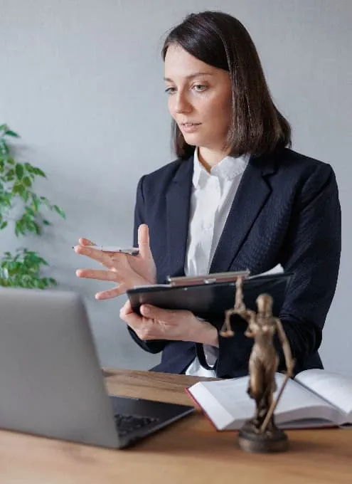 Avocate en rendez-vous à distance devant son ordinateur portable, une statuette de la Justice posée sur son bureau
